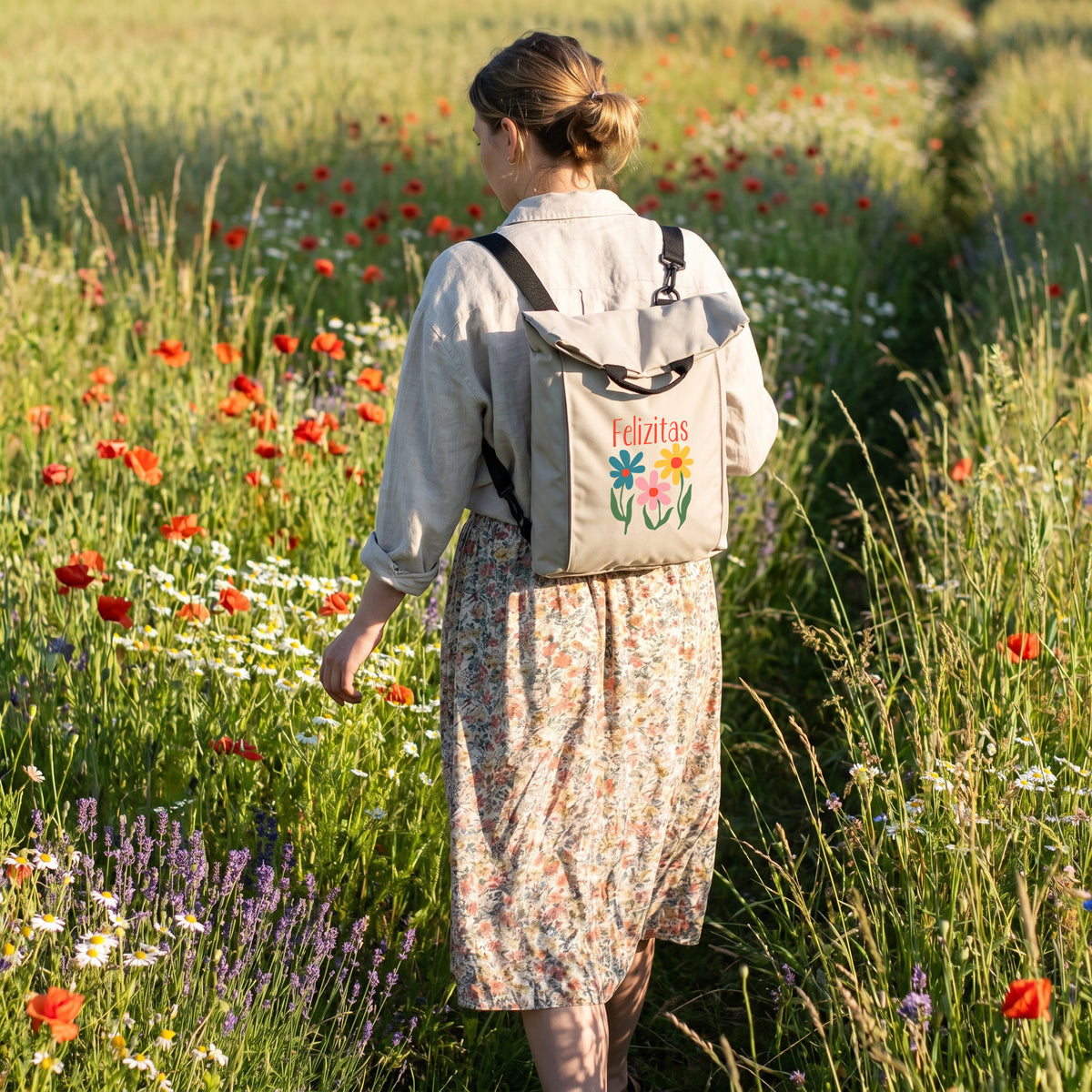 Beiger personalisierter Blumen Rucksack mit Name Felizitas auf dem Rücken einer Frau in einer blühenden Wiese
