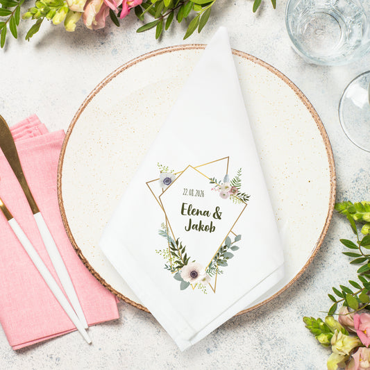 Stoffserviette Hochzeit mit Eukalyptus und Blumenrahmen sowie Namen und Datum auf Teller dekoriert