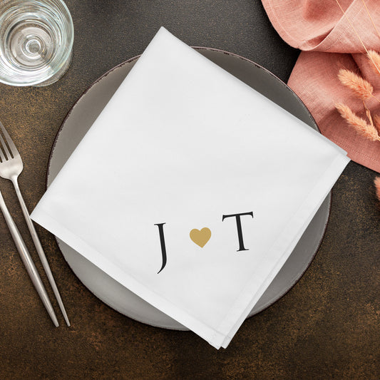 Weiße Hochzeitsserviette mit Initialen J und T und Herzmotiv als moderne Tischdekoration