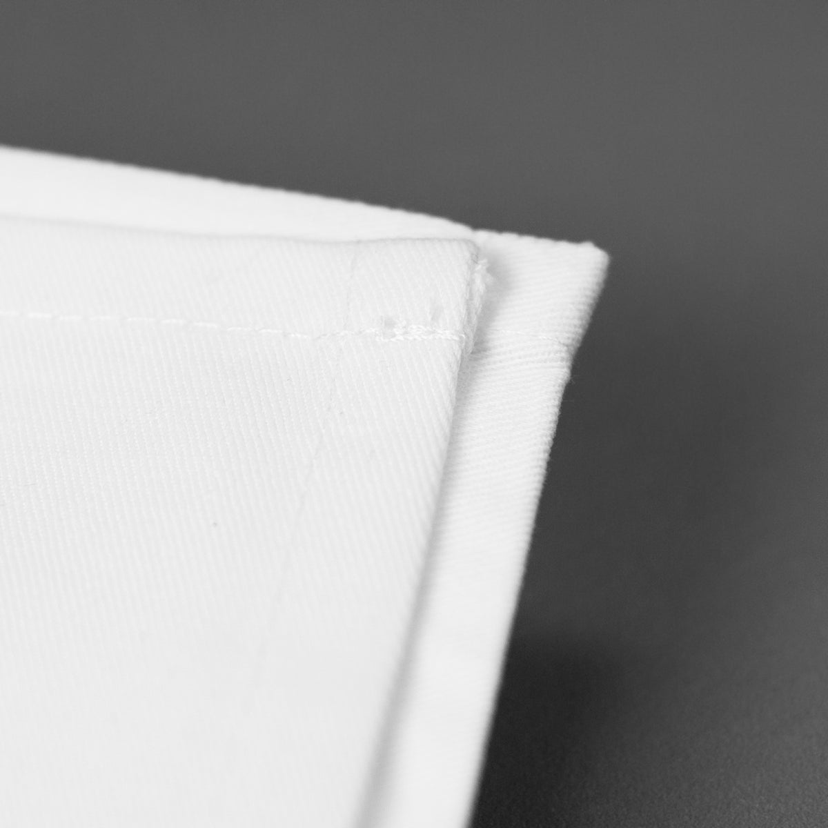 Detailaufnahme einer weißen Baumwollserviette mit sauber vernähter Kante
