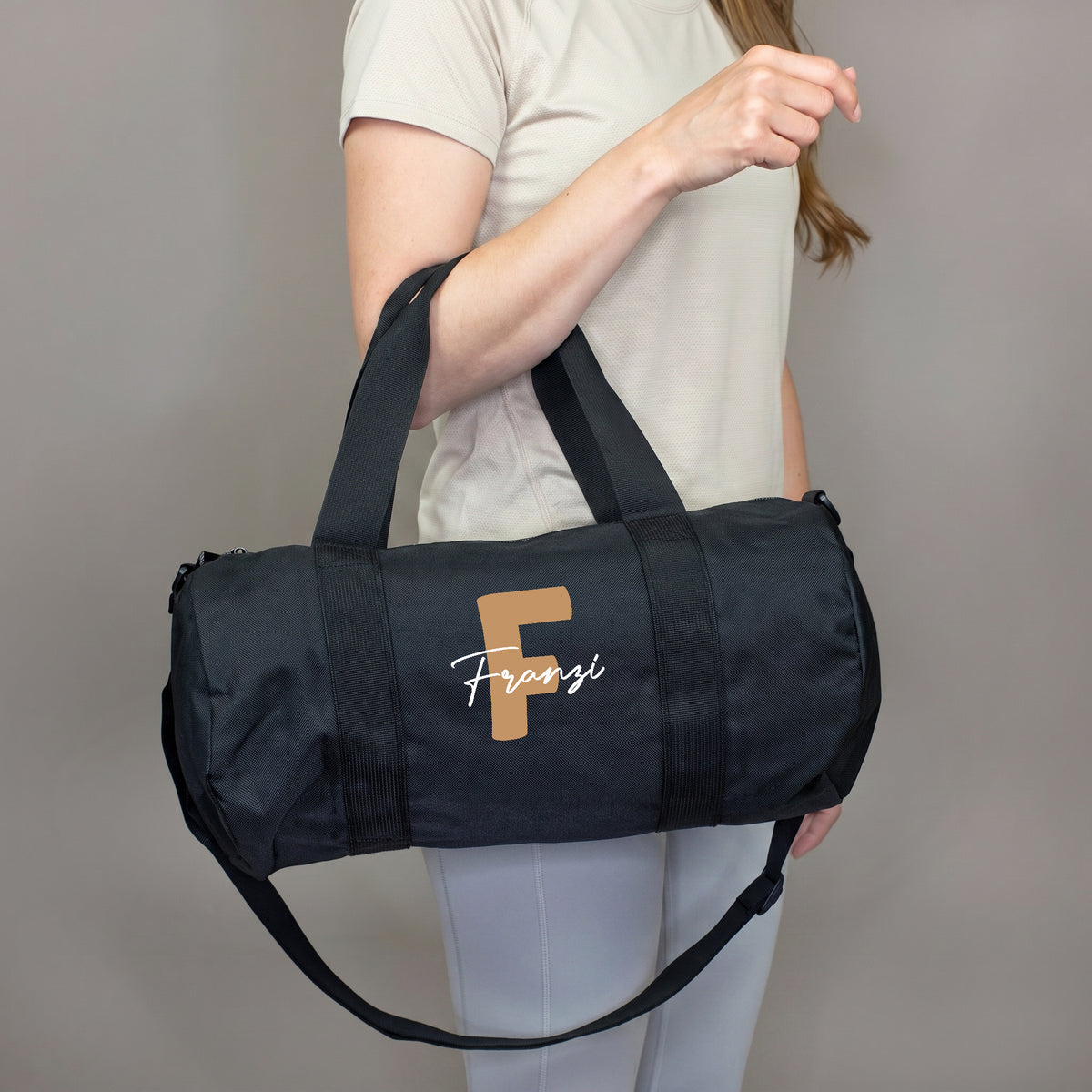 Personalisierte Sporttasche mit brauner Initiale F und Name Franzi, getragen am Arm als praktische Fitnesstasche
