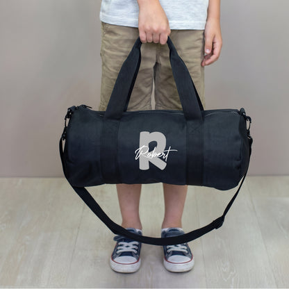 Schwarze Sporttasche für Kinder mit grauer Initiale R und Name Robert, getragen mit Schultergurt