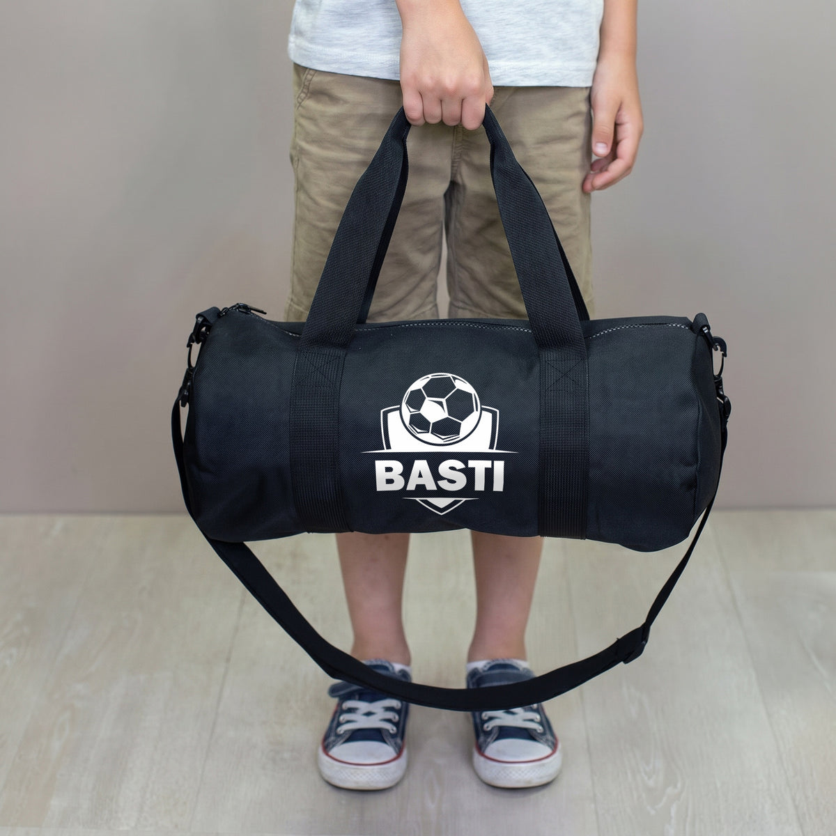 Kind hält personalisierte Fußballtasche mit Name Basti in der Hand