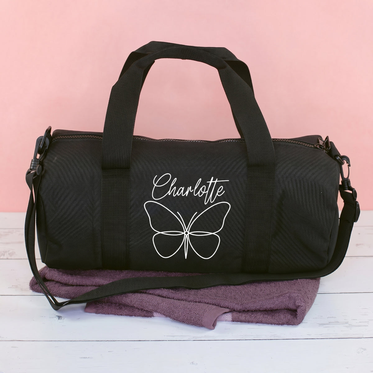 Schwarze Sporttasche mit Schmetterlingsmotiv und Name Charlotte auf rosa Hintergrund