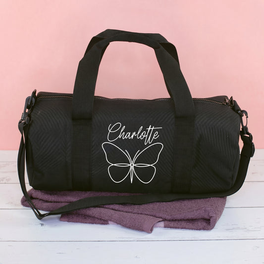 Schwarze Sporttasche mit Schmetterlingsmotiv und Name Charlotte auf rosa Hintergrund