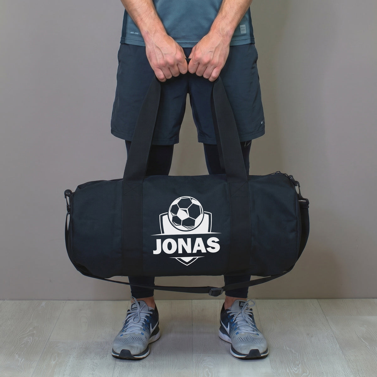 Mann hält personalisierte Fußballtasche mit Name Jonas in der Hand
