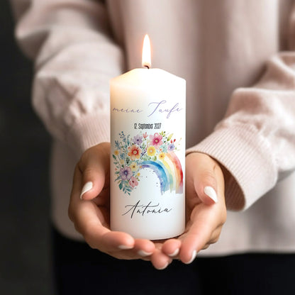 Taufkerze mit Regenbogenmotiv in Händen gehalten, beschriftet mit „Meine Taufe“, Datum und Name Antonia