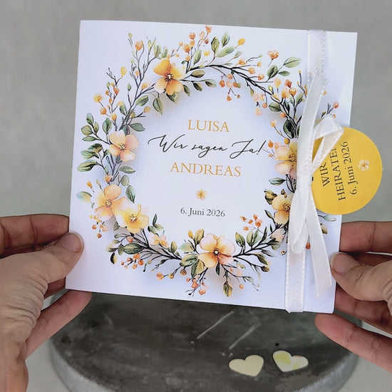 Hochzeitseinladung – Klappkarte mit gelbem Blumenkranz und Anhänger