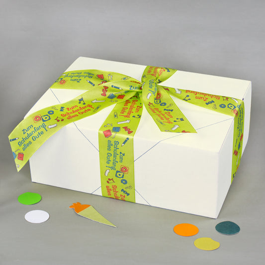 Weiß verpackte Geschenkbox mit grün-gelbem Geschenkband zum Schulanfang und bunten Schulmotiven