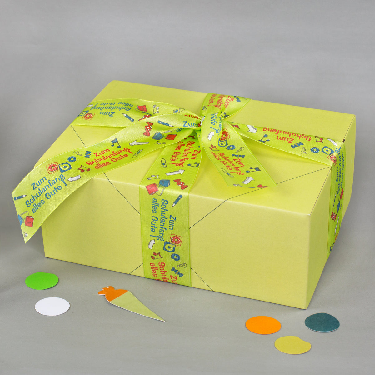 Gelbe Geschenkbox mit dekorativem Geschenkband zur Einschulung und Aufschrift Zum Schulanfang alles Gute