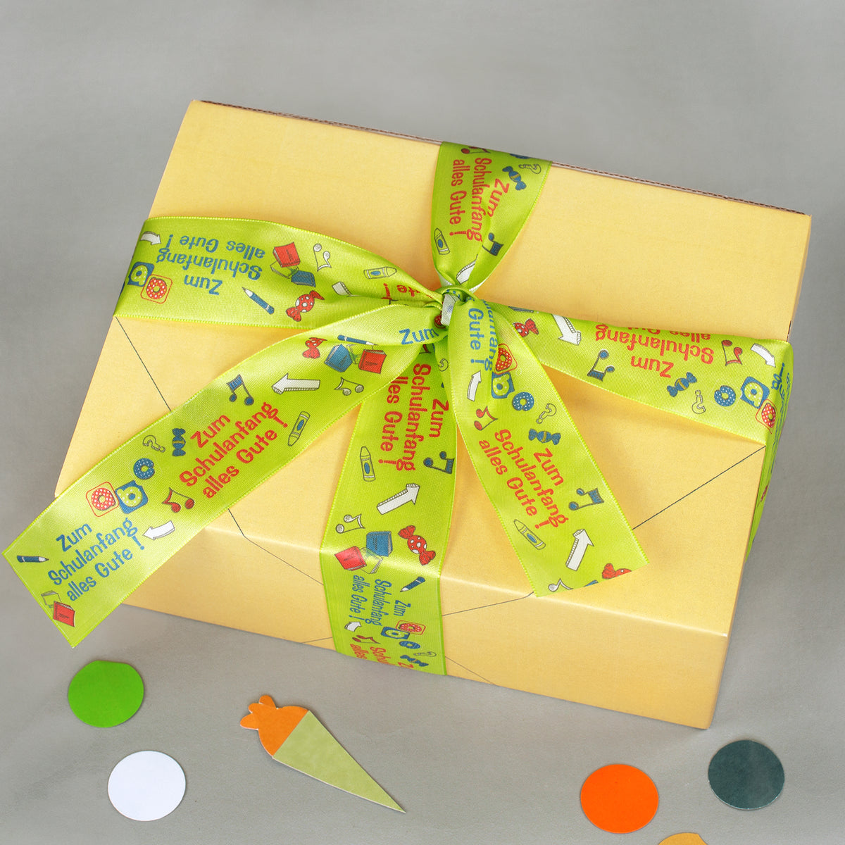 Gelbe Geschenkbox von oben mit Schleife aus Geschenkband für Schulanfang und Einschulung