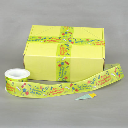 Geschenkband zur Einschulung als Dekoration an gelber Geschenkbox mit zusätzlichem Band auf Rolle
