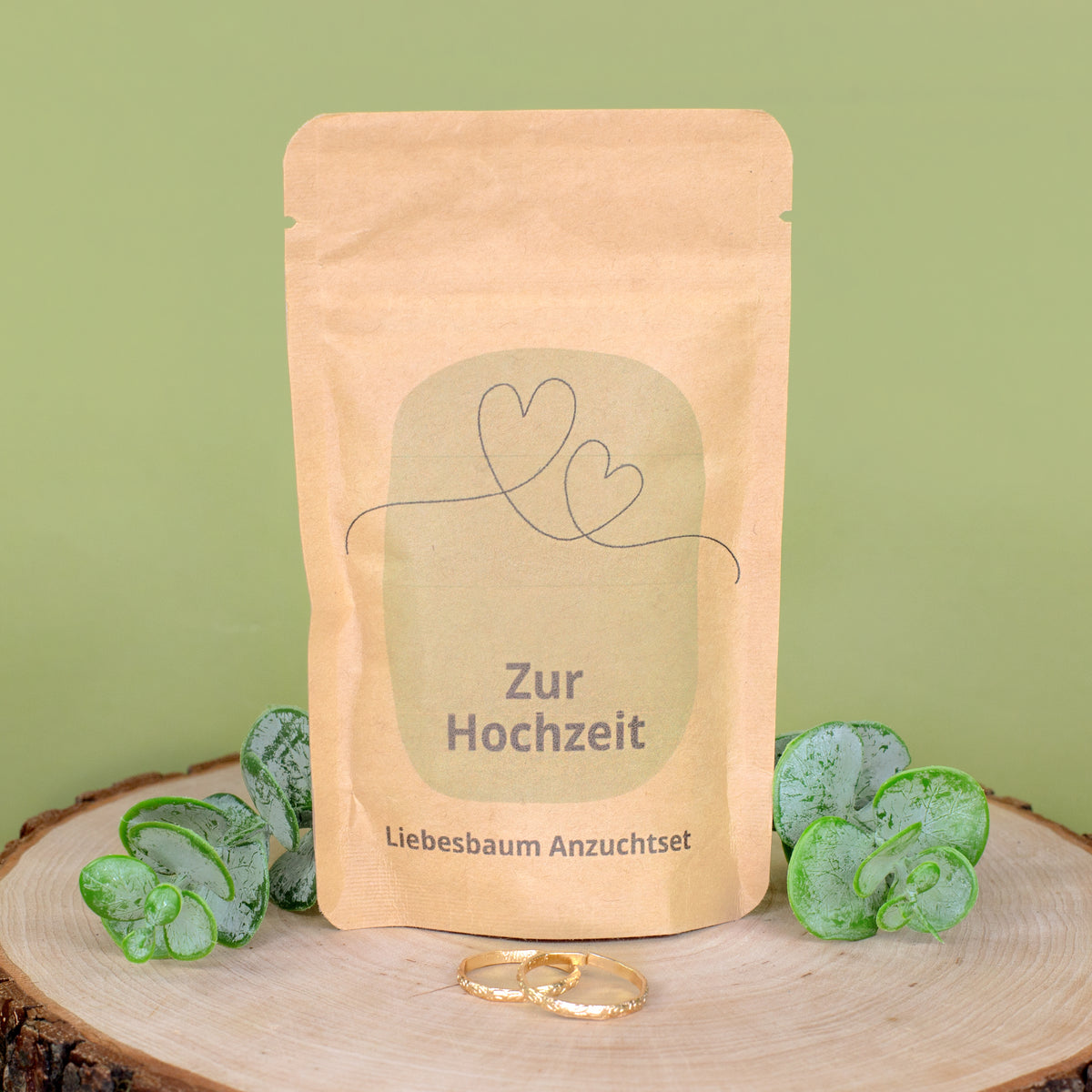 Liebesbaum Anzuchtset zur Hochzeit auf Holzscheibe mit grüner Deko und goldfarbenen Ringen